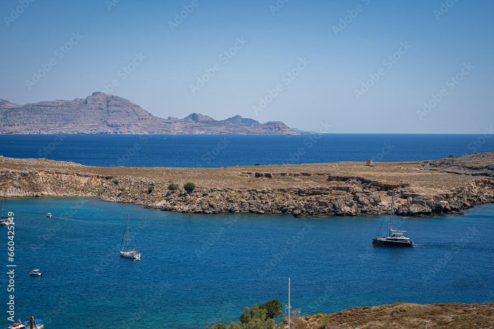 Enchanting Bay in Lindos, Rhodes: A serene Mediterranean retreat where moored boats meet the captivating turquoise embrace of the sea.