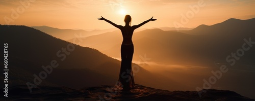 A woman standing on top of a mountain at sunset