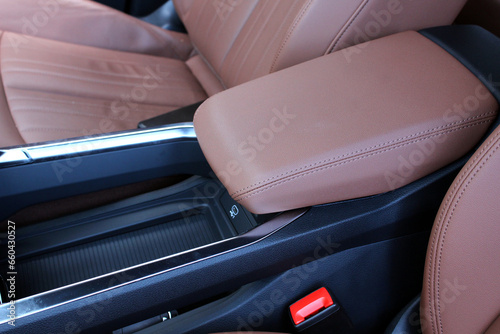 Electric car armrest. Electric Car inside. Premium electric car interior with light brown high-tech comfortable seats. Interior of prestige car. Comfortable perforated leather seats.