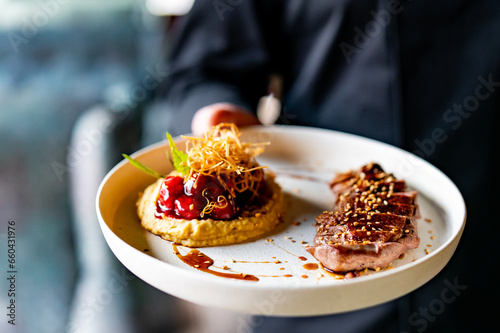 waiter or chef hold Duck fillet with hummus and cherry