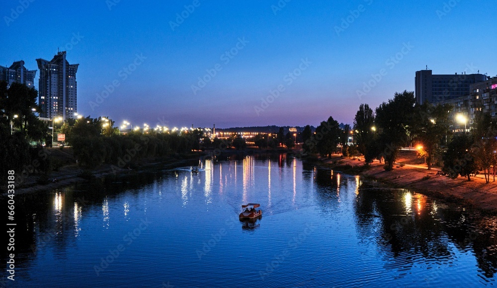 Night skyline of the city of Kyiv, Ukraine with boats sailing along the Dnieper River
