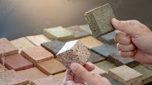 Designer hand comparing samples of sustainable decoration material made from rice straw. Natural texture and pattern for interior finishing design or building facade. Alternative material from nature