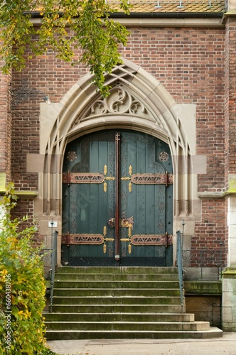 Brick building with two green doors featuring detailed and ornate designs