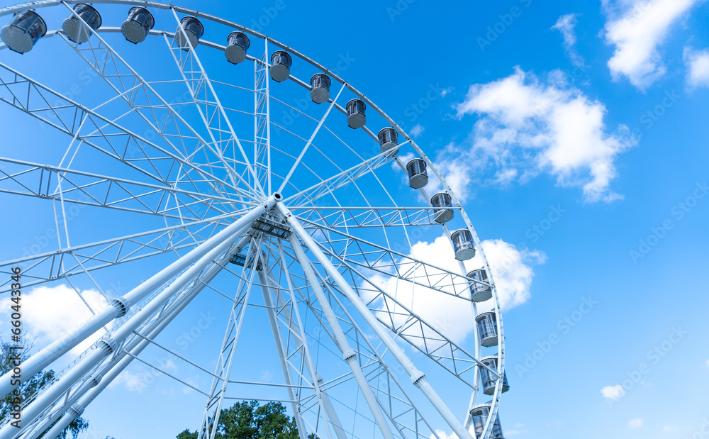 Big, tall white Ferris wheel in front of a perfect blue sky