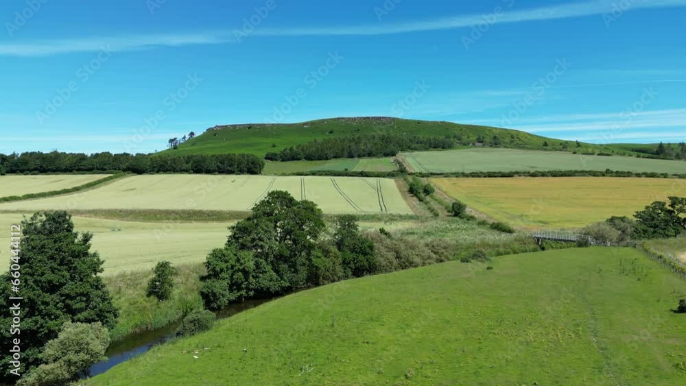 Drone shot over water canal in cultivated fields on the rolling hills under blue sky on a sunny day Drone shot over water canal in cultivated fields on the rolling hills under blue sky on a sunny day