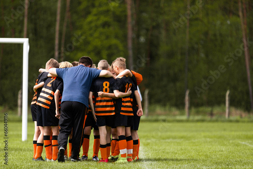 Group of school boys huddling united in soccer team before tournament football match. Boys in sports uniforms standing in a circle with coach © matimix