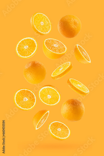 Bright oranges as flow fly or fall as art composition. Whole, half, round slices fruits on pastel orange background with shadow. Tropical fruits for advertising, design, label product, poster, card.