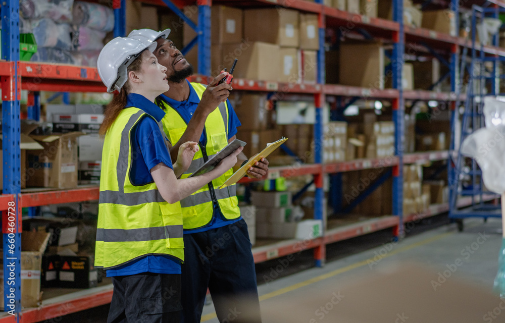 Distribution warehouse supervisor using tablet to check stock on storage shelf. Multiethnic man worker and colleague working together at storehouse discussing inventory as order. Diversity of people Distribution warehouse supervisor using tablet to check stock on storage shelf. Multiethnic man worker and colleague working together at storehouse discussing inventory as order. Diversity of people