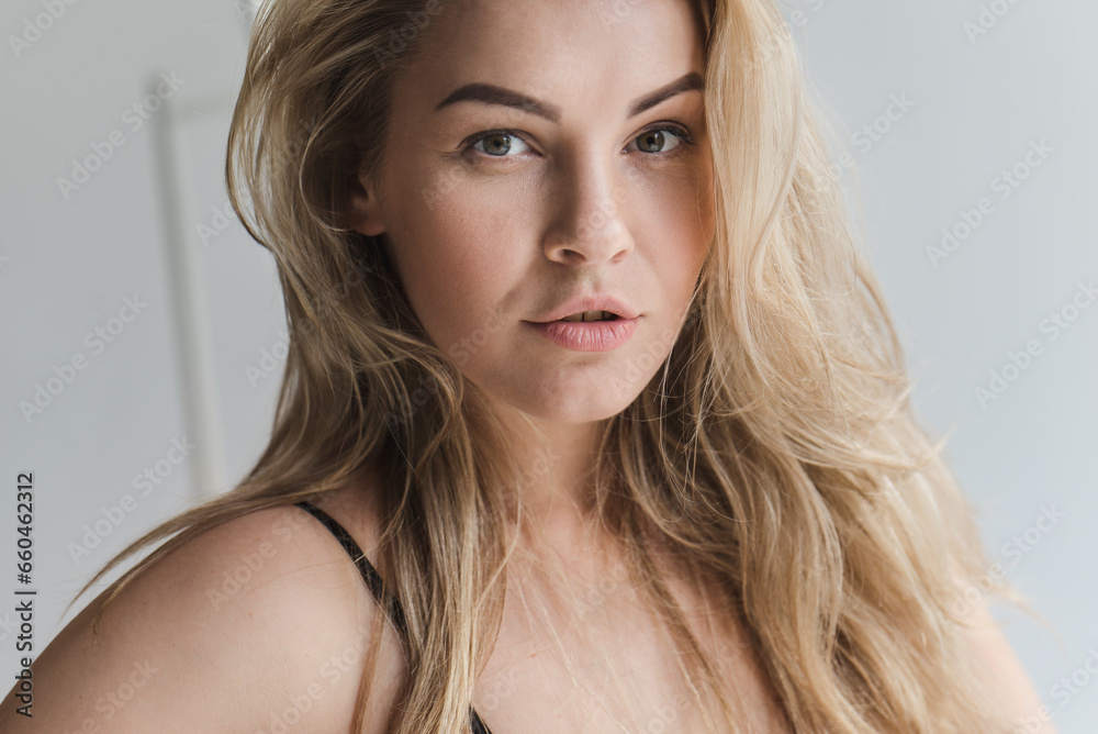 Naklejka premium emotional close-up portrait of a blonde woman with gorgeous hair. Sexy blonde smiles and enjoys life