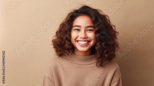 In this heartwarming portrait  a young teen girl s genuine smile takes center stage against a neutral studio background  a symbol of her youthful spirit and happiness.