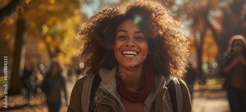 smiling young african american cute woman walking in a park in shiny autumnal day © MarianoMartin