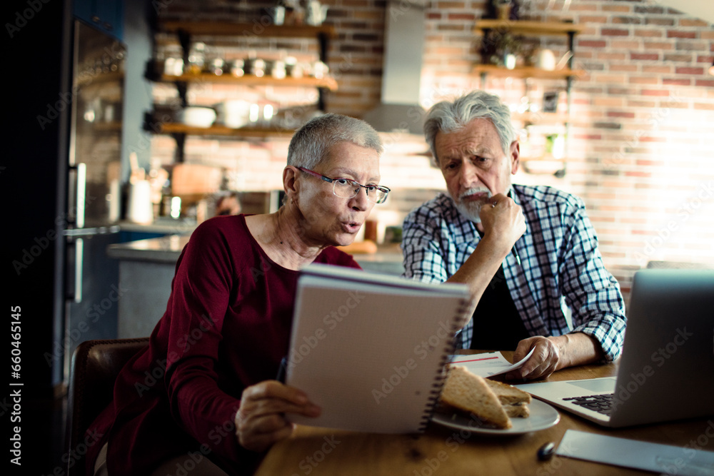 Senior couple doing bills and payments together in the kitchen at home Senior couple doing bills and payments together in the kitchen at home