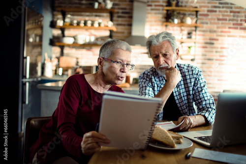 Senior couple doing bills and payments together in the kitchen at home