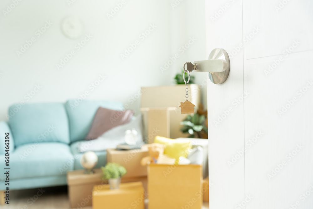 Fototapeta premium Moving house, relocation. The key was inserted into the door of the new house, inside the room was a cardboard box containing personal belongings and furniture. move in the apartment or condominium