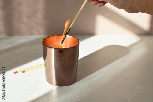 A woman lights an aromatherapy candle with a match.