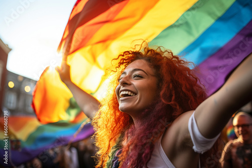 Amid the vibrant lights of a Pride festival, a woman exuberantly waves the rainbow flag, her joyous expression mirroring the colorful and accepting atmosphere.  photo