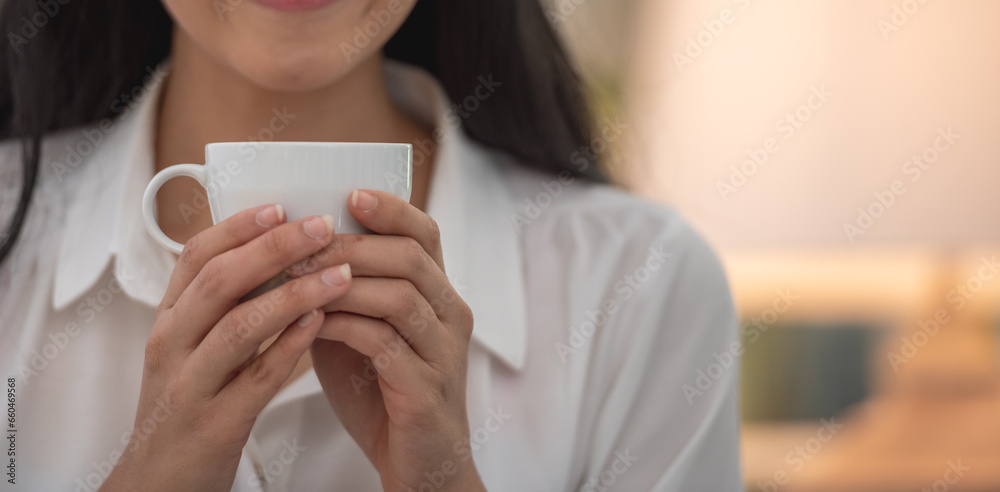 Banner of Asian woman Proprietor holding hot coffee in white ceramic cup to sniff smell of espresso in office work place . business owner entrepreneur girl carry coffee break to sniff fragrant smell Banner of Asian woman Proprietor holding hot coffee in white ceramic cup to sniff smell of espresso in office work place . business owner entrepreneur girl carry coffee break to sniff fragrant smell