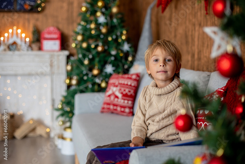 Beautiful blond child, young school boy, playing in a decorated home with knitted toys