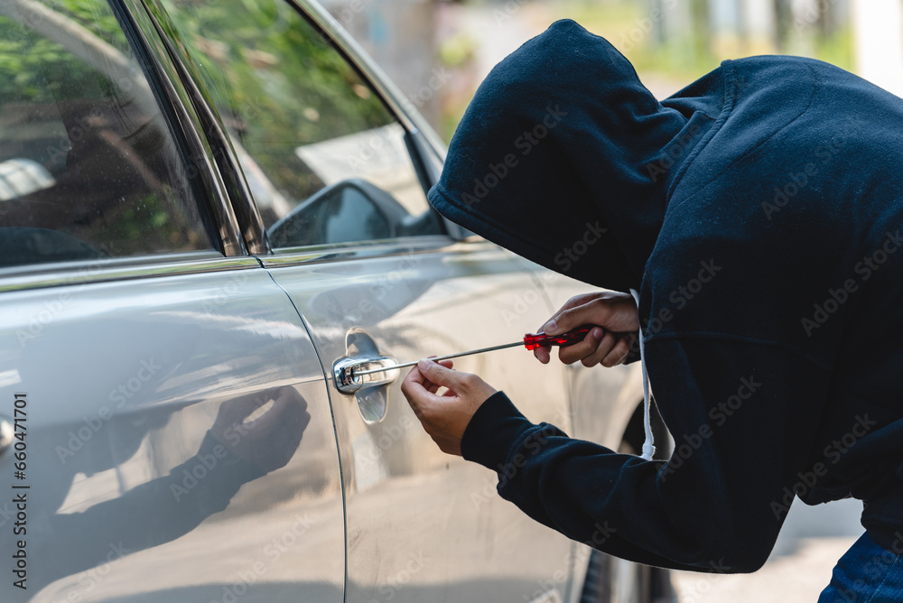 Car thief with mask steal robber trying to open car door by screwdriver . Thieves try to breaking window car door at danger car parking vandalism looting. Car thief with mask steal robber trying to open car door by screwdriver . Thieves try to breaking window car door at danger car parking vandalism looting.
