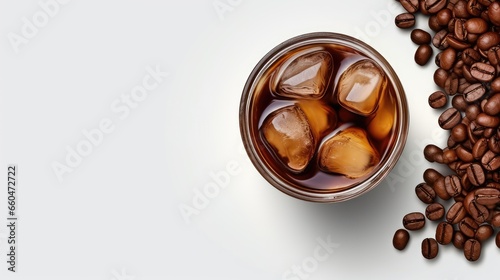 Top view of cold brewed iced coffee and coffee beans in glass jar on white surface with empty space
