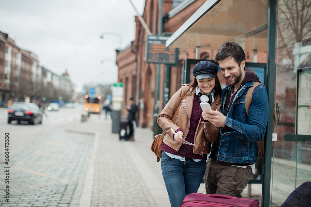 Young tourist couple using a smartphone at the bus stop