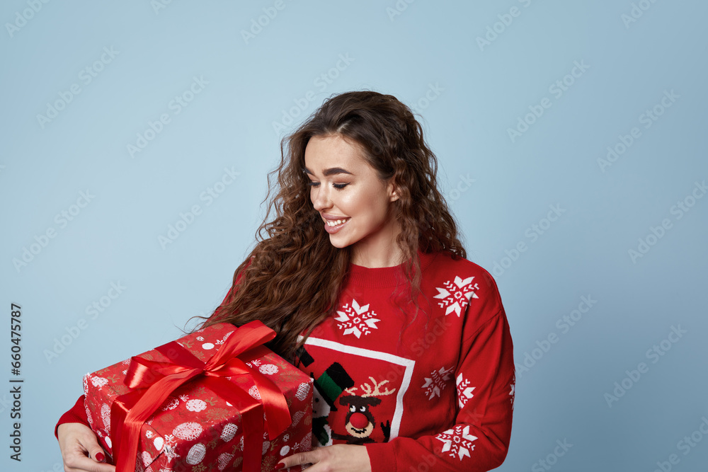 Happy Woman Holding Gift Box Over Blue Studio Background. Christmas Gift. Girl With A Present. New Year And Xmas Gifts Concept Happy Woman Holding Gift Box Over Blue Studio Background. Christmas Gift. Girl With A Present. New Year And Xmas Gifts Concept