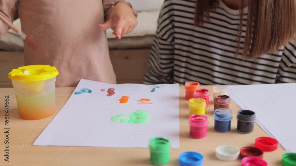 Creative time with mom. Teaching kids to paint. Art projects for toddlers and parents. Unknown mother with her little baby daughter painting together in home interior. Creative time with mom. Teaching kids to paint. Art projects for toddlers and parents. Unknown mother with her little baby daughter painting together in home interior.