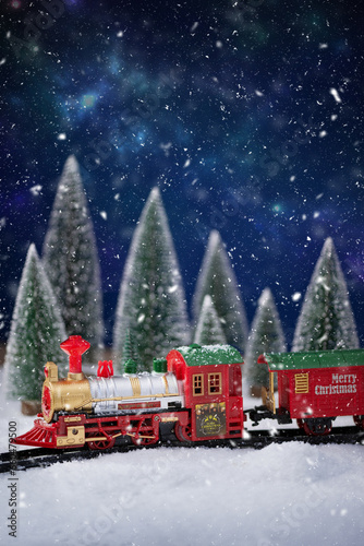 Toy train on railway in the snow with Christmas tree. Christmas and New Year background. Creative winter Christmas composition.