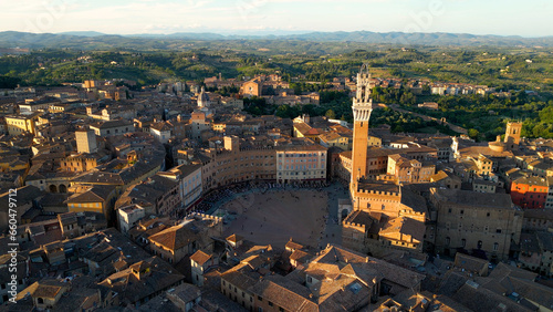 Aerial view of Torre del Mangia (Mangia Tower) in Piazza del Campo (Campo Square) in Siena, Tuscany, Italy. Drone orbit shot at sunset