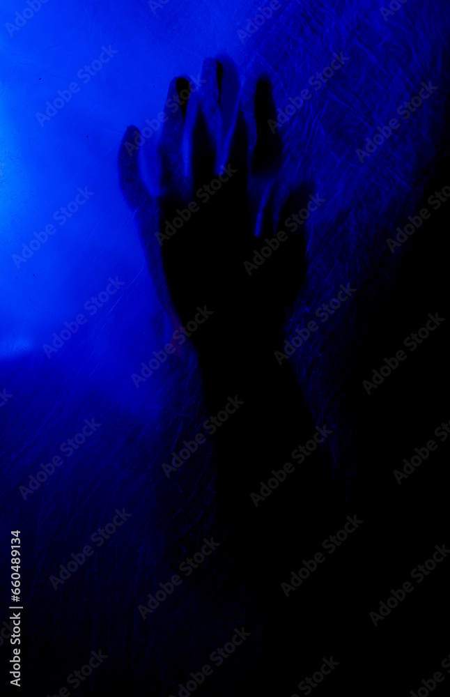 Arms of woman pressing against curtain. silhouette woman behind blue light poses mysteriously and artistically