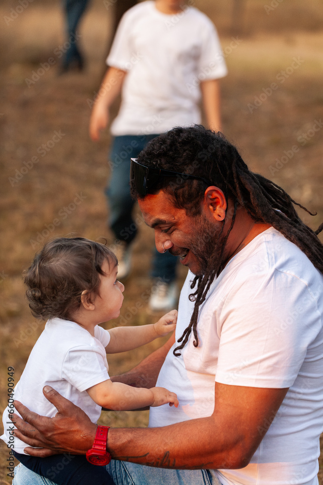 Happy Aussie baby girl with aboriginal father smiling together in soft sunset light Happy Aussie baby girl with aboriginal father smiling together in soft sunset light