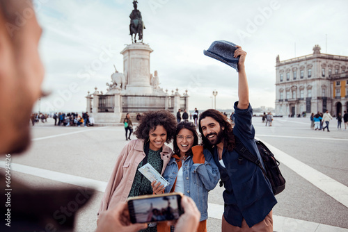 Diverse trio of young friends posing for a picture in front of the King Jose I statue on vacation in Lisbon photo