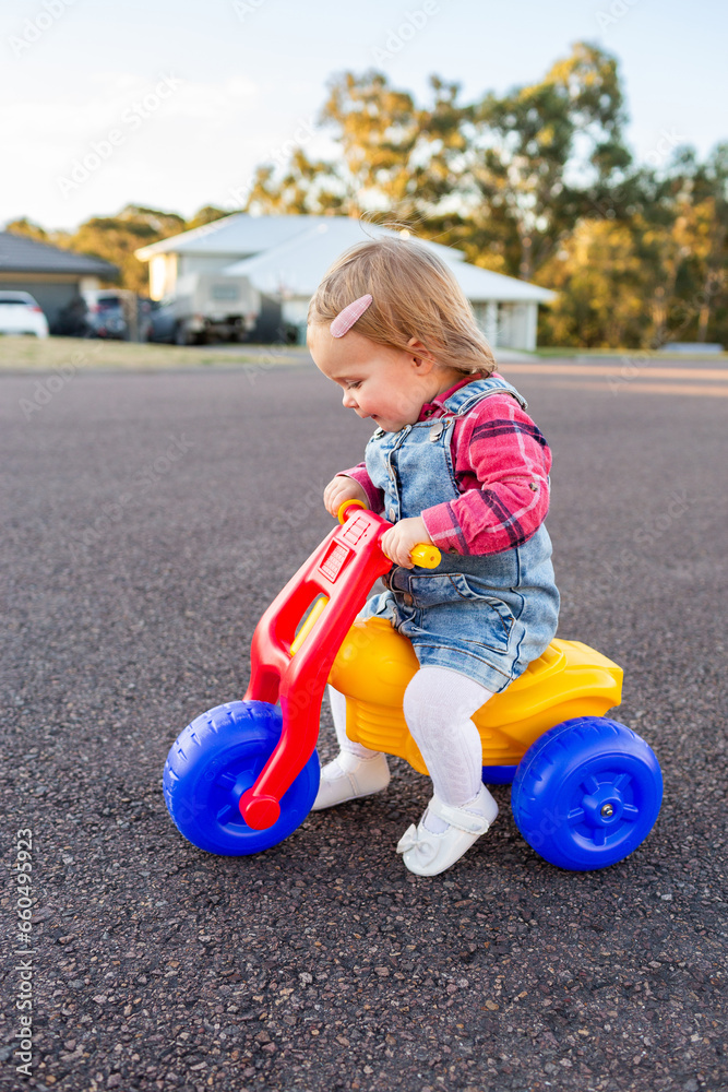 Young toddler girl riding on dune buggy tricycle on quiet urban road Young toddler girl riding on dune buggy tricycle on quiet urban road