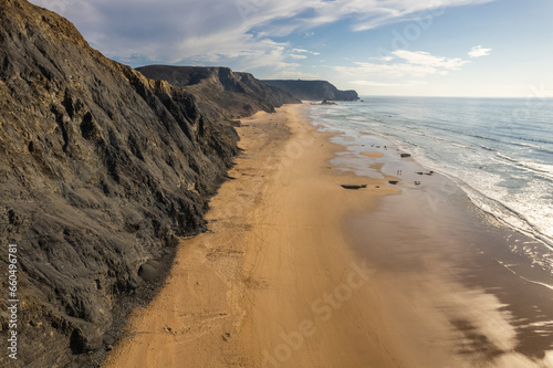 Sandy beach and dramatic cliffs on Atlantic Ocean coastline in Portugal. Aerial drone view