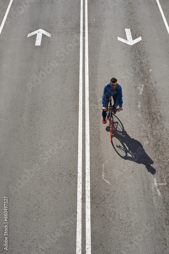 From above, young man ride his bicycle on roadway