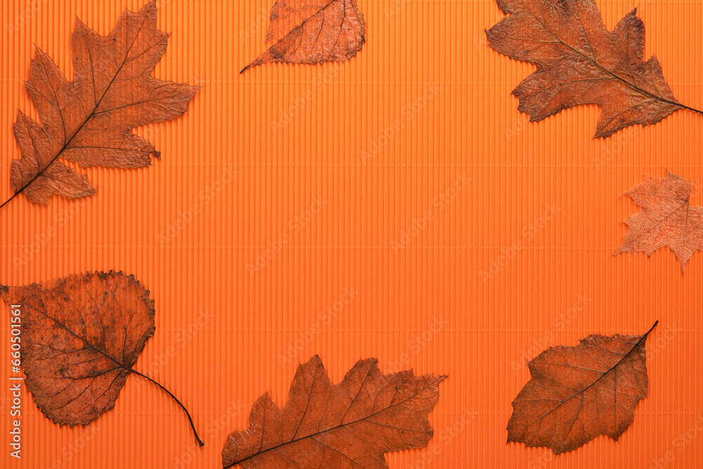 Halloween holiday background. Orange pumpkin, bat with funny eyes, spider, spider web, old leaves and branches from scary forest on orange background. Happy halloween card. Autumn decoration. Top view