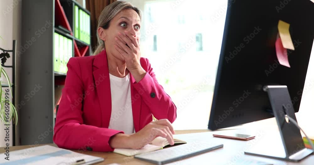 Confused business woman with online problem or email spam. Office worker shocked by frozen computer and confused by scam message or virus