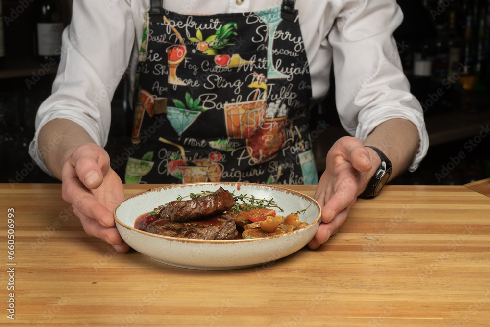 Steak on a plate in the hands of a bartender, restaurant menu