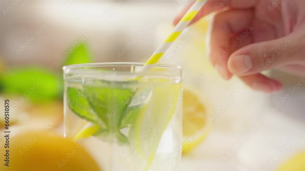 Lemonade. A young woman decisively adds a straw to a ready-made cocktail in the kitchen of a private house. Young woman adding paper straw to ready-made mojito lemonade new salad recipes, tropical Lemonade. A young woman decisively adds a straw to a ready-made cocktail in the kitchen of a private house. Young woman adding paper straw to ready-made mojito lemonade new salad recipes, tropical