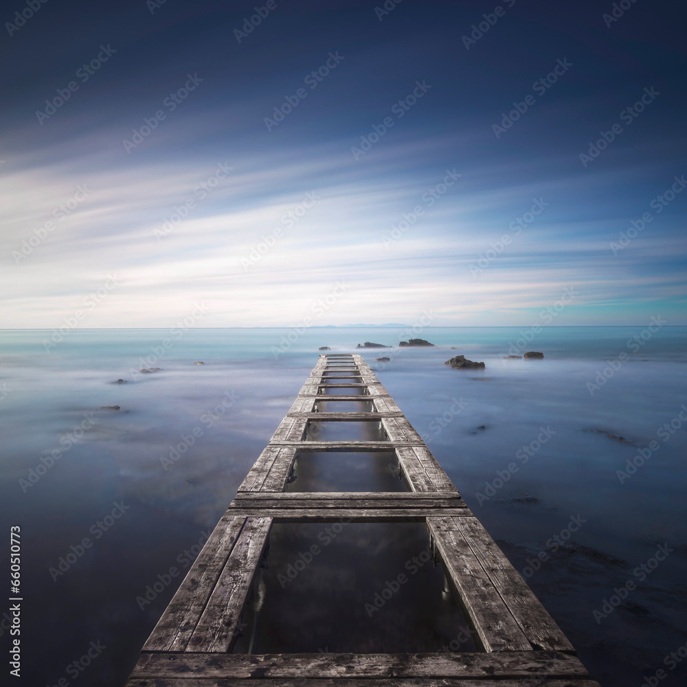 Wooden pier remains in a blue sea. Long Exposure.
