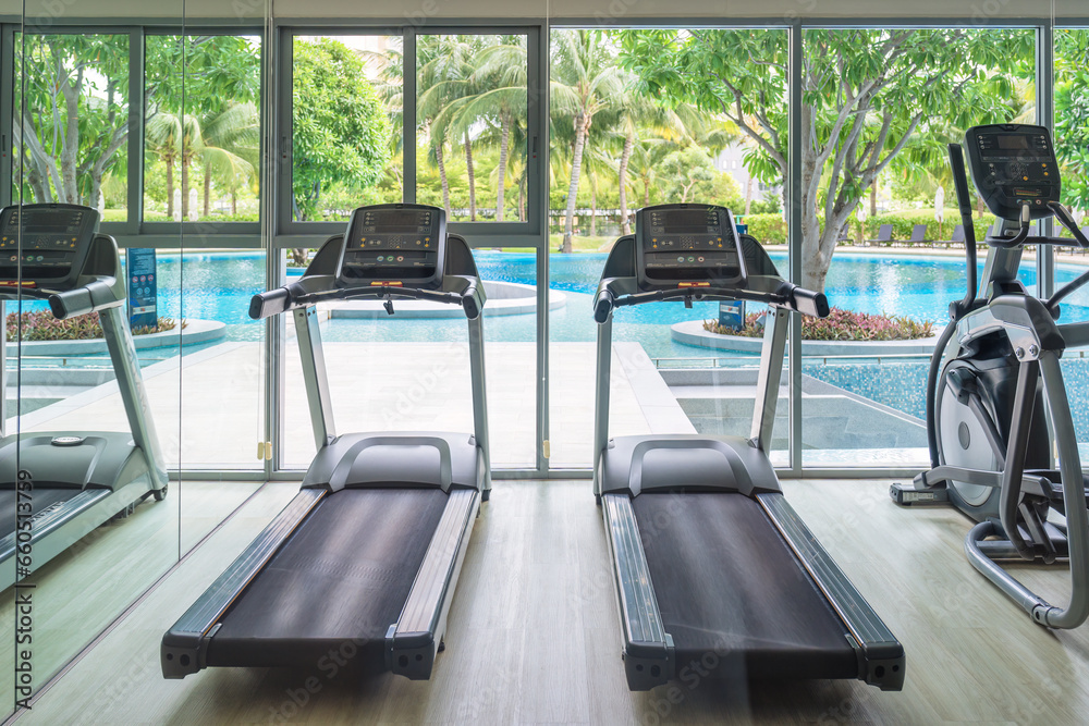 Fototapeta premium Row of treadmill machine and glass window with garden view in gym