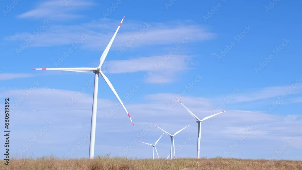 Fleet of power generators in motion. The blades of the wind farm rotate against the sky. The concept of extracting electricity from renewable sources. Wind turbine to generate electricity. Fleet of power generators in motion. The blades of the wind farm rotate against the sky. The concept of extracting electricity from renewable sources. Wind turbine to generate electricity.
