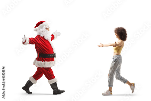 Full length profile shot of santa claus walking with arms wide open and meeting a gen z female