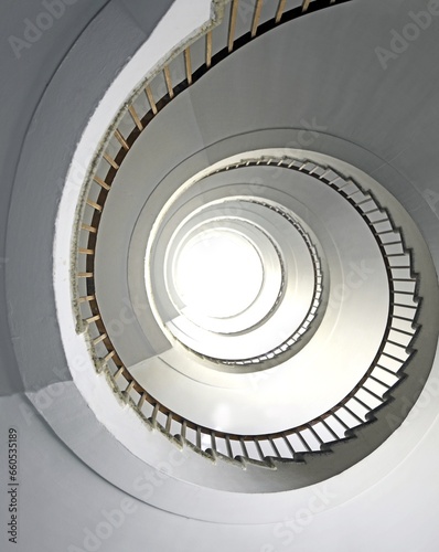 spiral staircase going up vertically without people and white light at the top