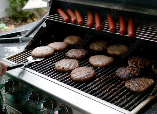 Hamburgers and hot dogs being grilled on barbecue