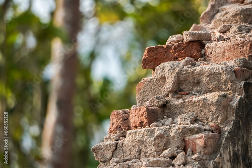 The ruins of an old house wall showing the bricks with bokeh backgrounds. Broken destroyed building walls are weathered and in poor condition. Empty blank copy text space.