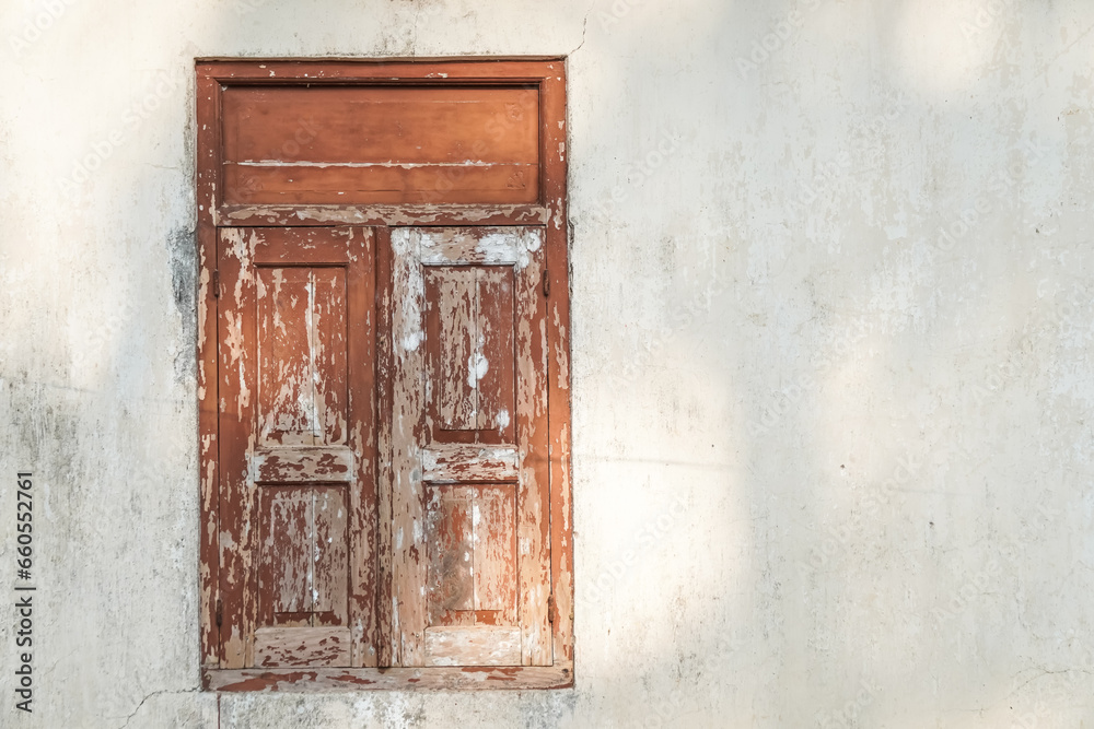 Closed old Javanese wooden window with shutters on an moldy white concrete wall. Concept for traditional exterior, vintage, heritage, rural housing ornament. Empty blank copy text space. Omah Joglo