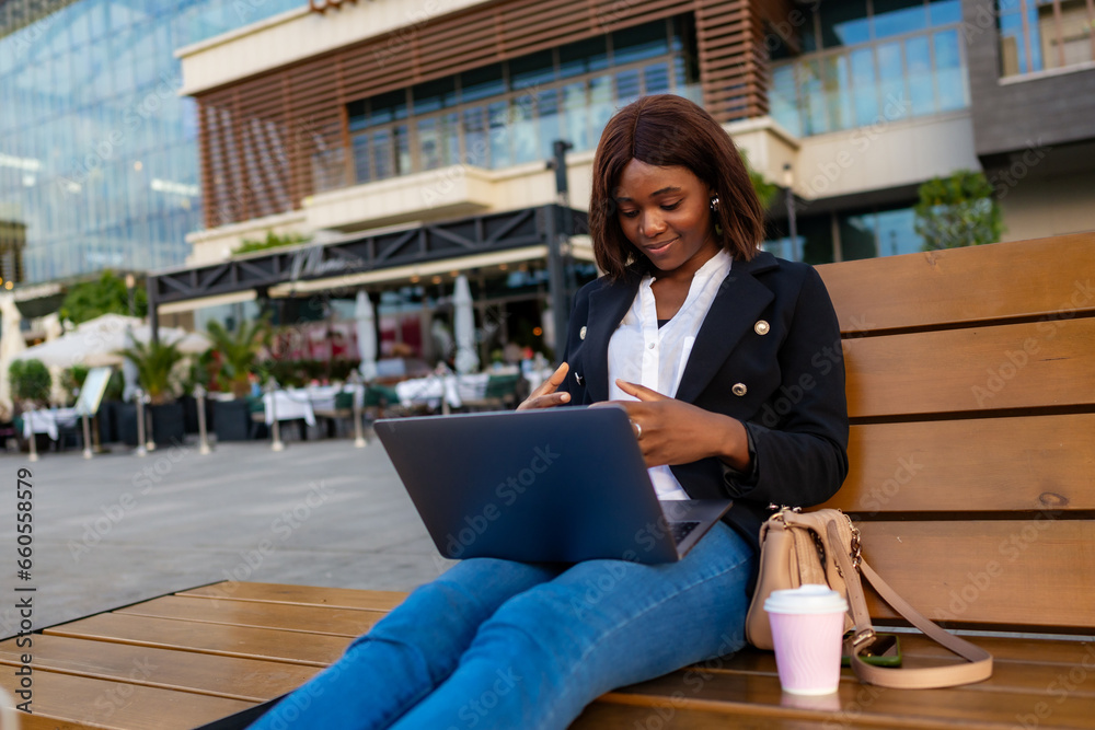 Fototapeta premium In the urban backdrop, the freelance businesswoman continues her work by participating in a video call while seated outdoors.