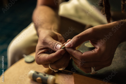 Close up of the hands of a goldsmith showing a precious stone for the elaboration of a jewel.