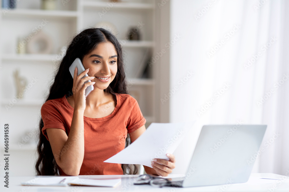 Happy Young Eastern Woman Talking On Smartphone Holding Paper Happy Young Eastern Woman Talking On Smartphone Holding Paper